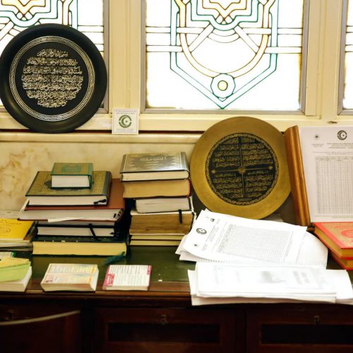 Una mesa y muchos libros contra el muro de orientación a La Meca, o quibla